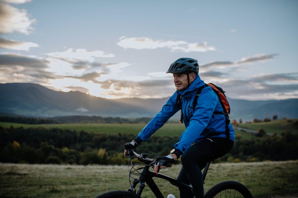 Active senior man biker riding bike in nature on autumn day